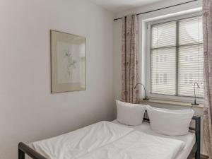 a bedroom with a bed with white sheets and a window at Objekt-Nr 247 - Hafen - Kurgartenstraße in Travemünde