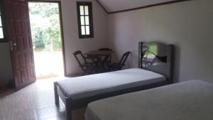 two beds in a room with a table and chairs at Chales Flores de Sana in Sana