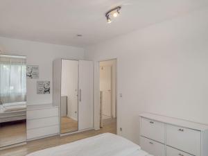 a white bedroom with white furniture and a mirror at Objekt-Nr 86 - Priwall - Wiekstraße in Priwall