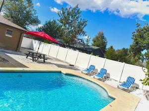 a swimming pool with two chairs and a red umbrella at Island 1 in Kissimmee