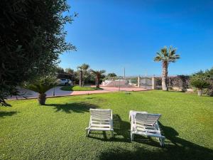 two white chairs sitting on a lawn with palm trees at VILLA GIUDICE Luxury Home with Private Pool in Priolo Gargallo