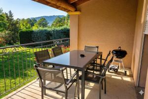 a table and chairs on a balcony with a grill at Ombre Bleue Du Figuier, Ailhon in Ailhon