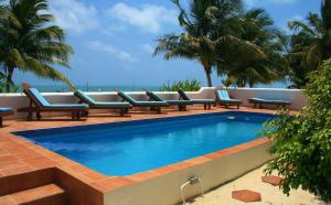a swimming pool with lounge chairs and the ocean at Seaside Villas in Caye Caulker