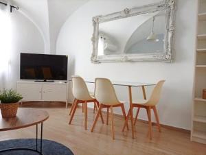 a dining room with a table and chairs and a mirror at Apartamentos La Machacona Plaza Mayor recién reformados in Cáceres