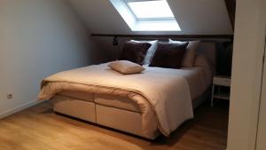 een slaapkamer met een groot bed en een dakraam bij Ypres Ramparts House in Ieper