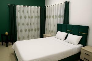 a bedroom with a large bed with green and white curtains at Akany Fitahiantsoa in Ivato