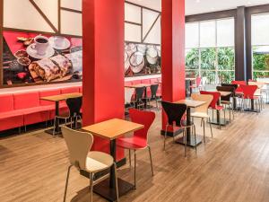 a restaurant with red walls and tables and chairs at ibis Blumenau in Blumenau
