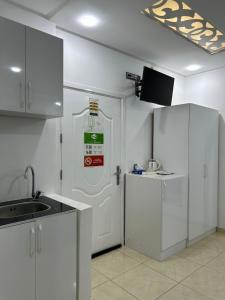 a kitchen with white cabinets and a white door at فندق الشموخ Hotel Al Shmokh in Aousserd