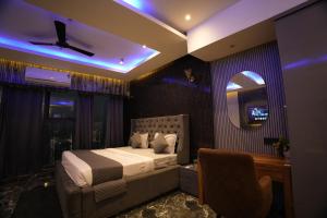a bedroom with a bed and a chair and a mirror at Hotel Namaste With Jacuzzi I Best For Couples and Corporate I Noida in Noida +35 photos