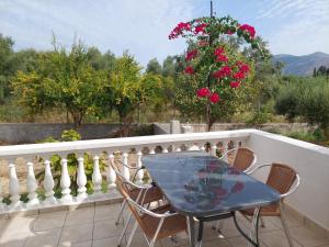 a table and chairs on a balcony with roses at NATALIA in Lixouri