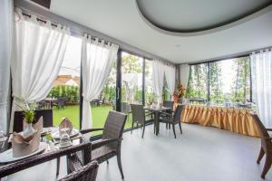 a dining room with tables and chairs and large windows at D11 Hotel in Phitsanulok