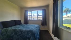 a bedroom with a bed and a window at Bach 30 at Waimārama Beach in Waimarama