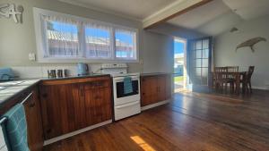 a kitchen with wooden cabinets and a stove top oven at Bach 30 at Waimārama Beach in Waimarama