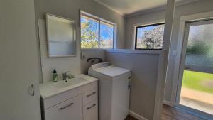 a small bathroom with a washing machine and a sink at Bach 30 at Waimārama Beach in Waimarama +20 photos