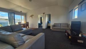 a living room with a couch and a tv at Bach 30 at Waimārama Beach in Waimarama