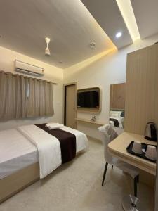 a bedroom with a bed and a desk and a tv at Samyak Stay in Ujjain