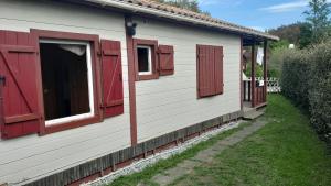 a house with red shuttered windows and a yard at Le chalet Paradis in Estang