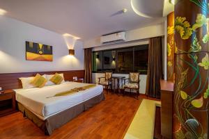 a hotel room with a bed and a dining room at The Ligor City Hotel in Nakhon Si Thammarat