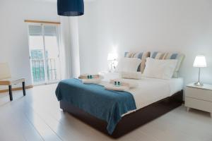 um quarto branco com uma cama com toalhas em Apartamento Vista Mar em Olhão