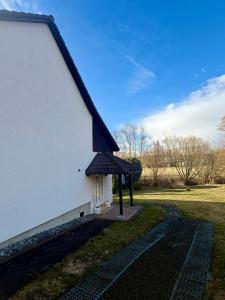 a white building with a black roof and a field at U potůčku in Ledce