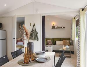 a dining room with a table and a living room at Camping La Prévoté in Saint-Hilaire-de-Riez