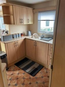 a small kitchen with wooden cabinets and a window at Happy Days Caravan Park - Lovely Spacious 3 Bed Caravan in Chapel Saint Leonards