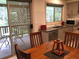 a kitchen with a wooden table and a balcony at Emerald Creek Cottages in Emerald