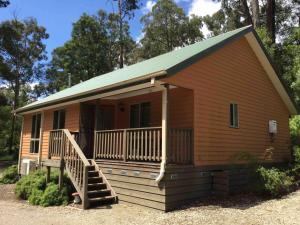 Casa pequeña con porche y escalera en Emerald Creek Cottages, en Emerald