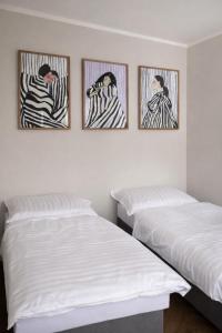 three framed pictures on a wall above two beds at Studio Odrodzenia 5 Centrum Lubina in Lubin
