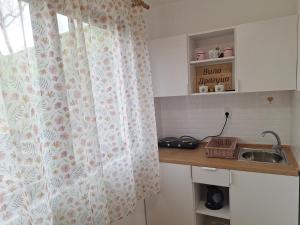 a kitchen with a curtain on a window and a sink at Vila Dragica in Bogutovac +14 photos
