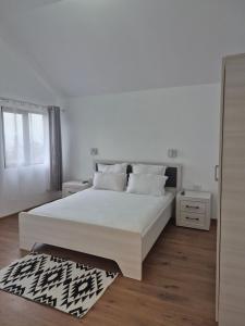 a white bedroom with a large bed and a window at La Miruna in Comăneşti
