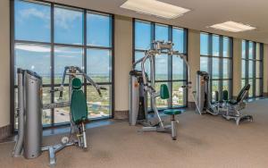 a gym with cardio equipment in a building with windows at The Oasis at Orange Beach 2006 (Phoenix West II) in Orange Beach