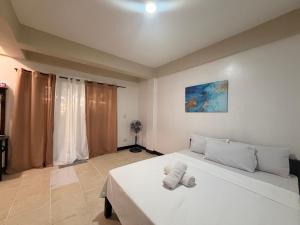 a bedroom with a white bed and a fan at Boracay Garden Retreat in Boracay