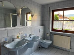 a bathroom with two sinks and a toilet and a window at Ferienwohnung Sonnenblick in Grafenwiesen +22 photos