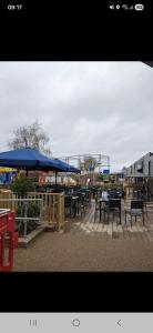 a group of tables and blue umbrellas on a patio at Highfield Grange Holiday Park in Little Clacton