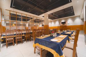 a restaurant with tables and chairs with blue tablecloths at Hotel Apsara in Kizhake Chālakudi +29 photos