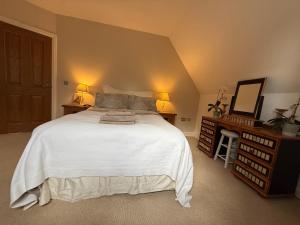 a bedroom with a large white bed with two lamps at Silsoe Cottage B&B - Woodland View Room in Silsoe