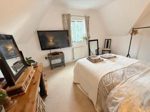 a bedroom with a bed and a flat screen tv at Silsoe Cottage B&B - Woodland View Room in Silsoe