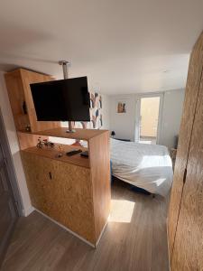 a bedroom with a bed and a desk with a television at Studio cosy avec balcon in Dunkerque