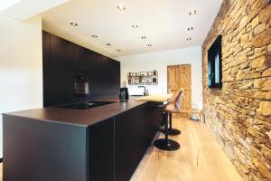 a kitchen with a black counter and a stone wall at La fagnette in Jalhay