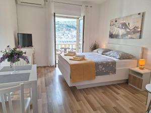 a bedroom with a bed and a table and a window at Apartments Villa Sirena in Dubrovnik