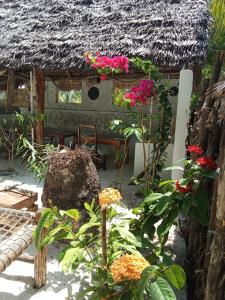 a garden with flowers in front of a thatched house at The Twende Villa on Beach in Paje +25 photos