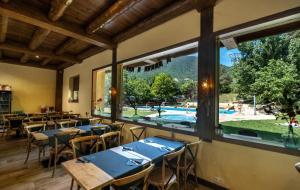 a restaurant with tables and a view of a pool at La Borda del Pubill Resort in Ribera de Cardós