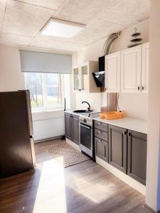 a kitchen with white cabinets and a black refrigerator at Mājīgs dzīvoklis Aizputē in Aizpute
