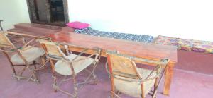 a wooden table with three chairs around it at The Twende Villa on Beach in Paje