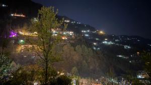 a view of a mountain at night with lights at Moksh Jibhi Retreat in Jibhi