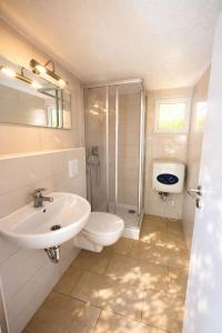 a bathroom with a sink and a toilet and a shower at Erholung pur in der Strandhussiedlung Rügen - Bungalow Ferienwohnung - bis 5 Personen - nur 100m zum Naturstrand - mitten im Kiefernwald - Ideal für Paare & Familien - Hunde herzlich willkommen in Dranske +18 photos