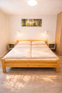 a wooden bed in a room with two tables at Erholung pur in der Strandhussiedlung Rügen - Bungalow Ferienwohnung - bis 5 Personen - nur 100m zum Naturstrand - mitten im Kiefernwald - Ideal für Paare & Familien - Hunde herzlich willkommen in Dranske