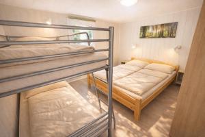 two bunk beds in a small room with a bed at Erholung pur in der Strandhussiedlung Rügen - Bungalow Ferienwohnung - bis 5 Personen - nur 100m zum Naturstrand - mitten im Kiefernwald - Ideal für Paare & Familien - Hunde herzlich willkommen in Dranske