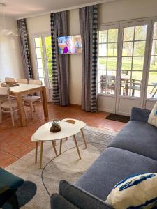 a living room with a couch and a table at Maison villa Lilou, Pierre et vacances, avec piscine, vue sur le golf, plage à 10 min à pied in Moliets-et-Maa